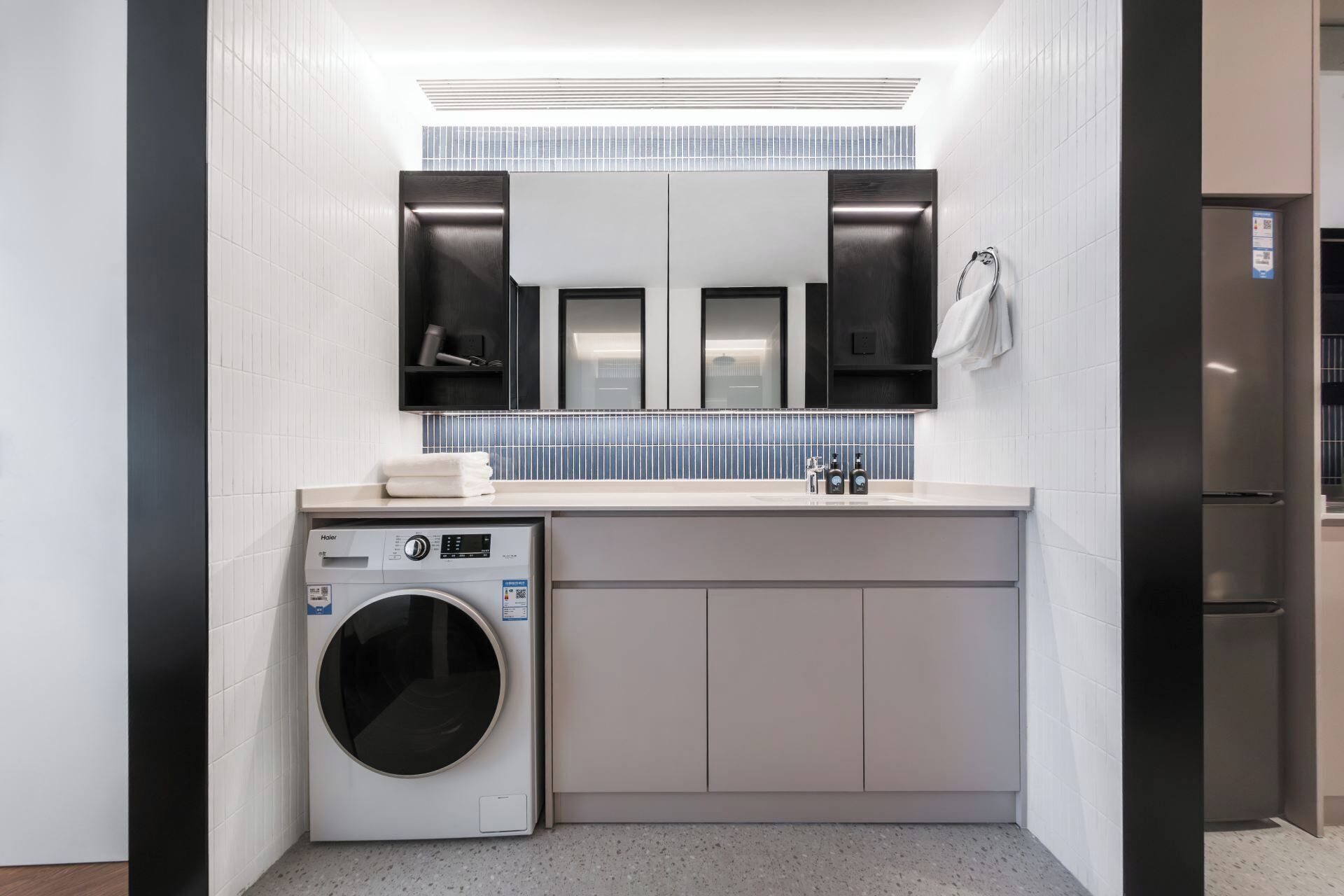 A modern bathroom with a washing machine, a sink, and a mirror.