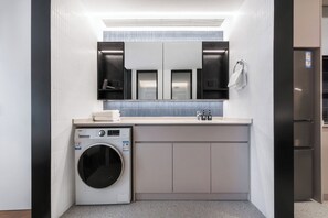 Casa de banho moderna com máquina de lavar, lavatório e espelho.
