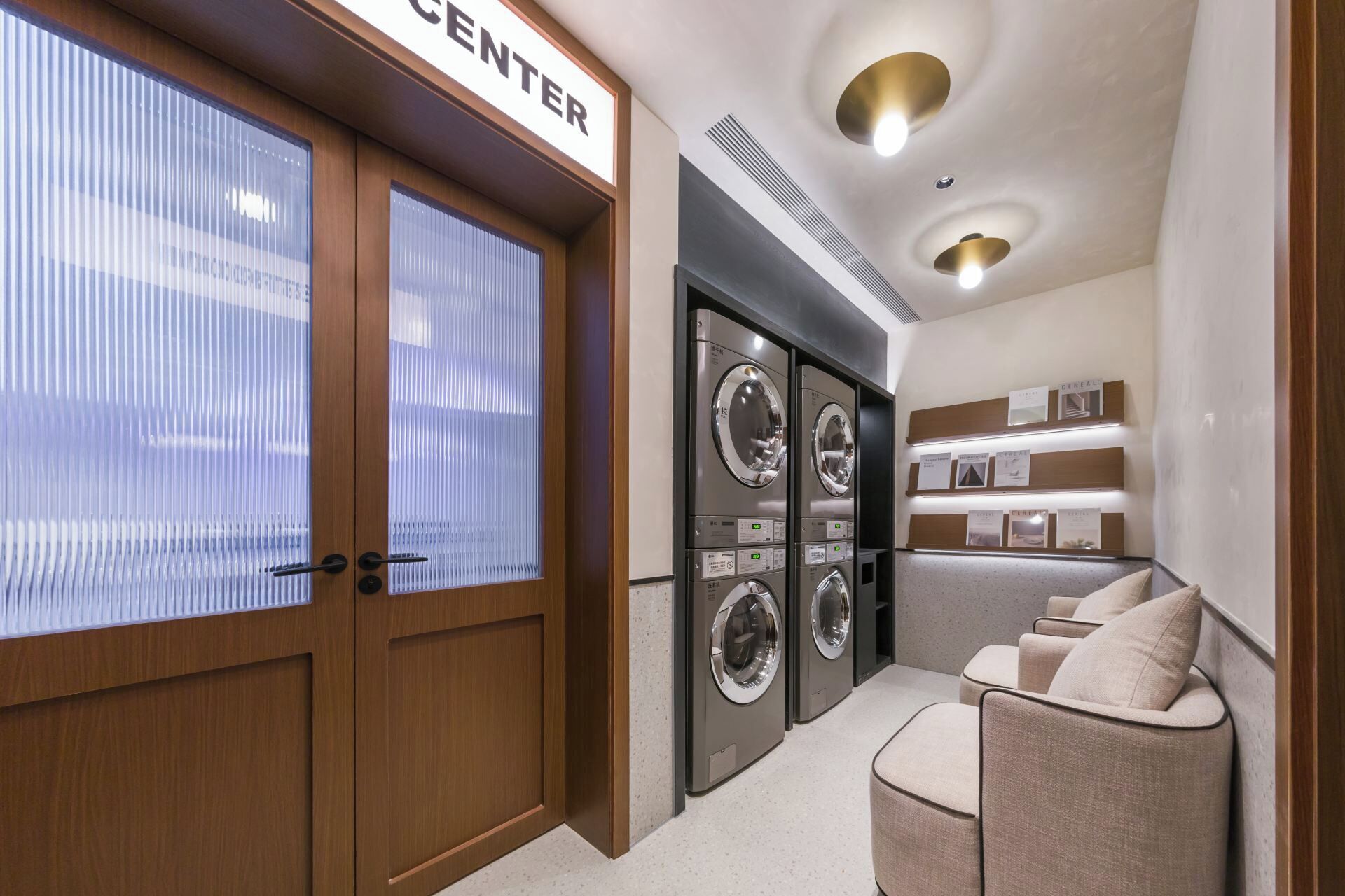 Un cuarto de lavado con puerta de madera, lavadora, secadora y una zona de estar con cojines.