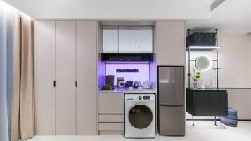 A compact kitchen with built-in appliances, a washing machine, and a compact refrigerator.