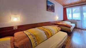 Quarto de hotel com duas camas, teto de madeira, pintura de montanhas e janela com cortinas.