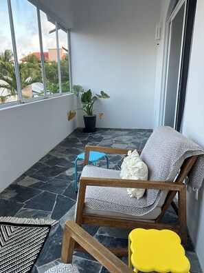 A balcony with a patterned sofa, a small table, a potted plant, and a view of the outside. - OTOMI HOUSE, PUERTO MORELOS (Puerto Morelos)