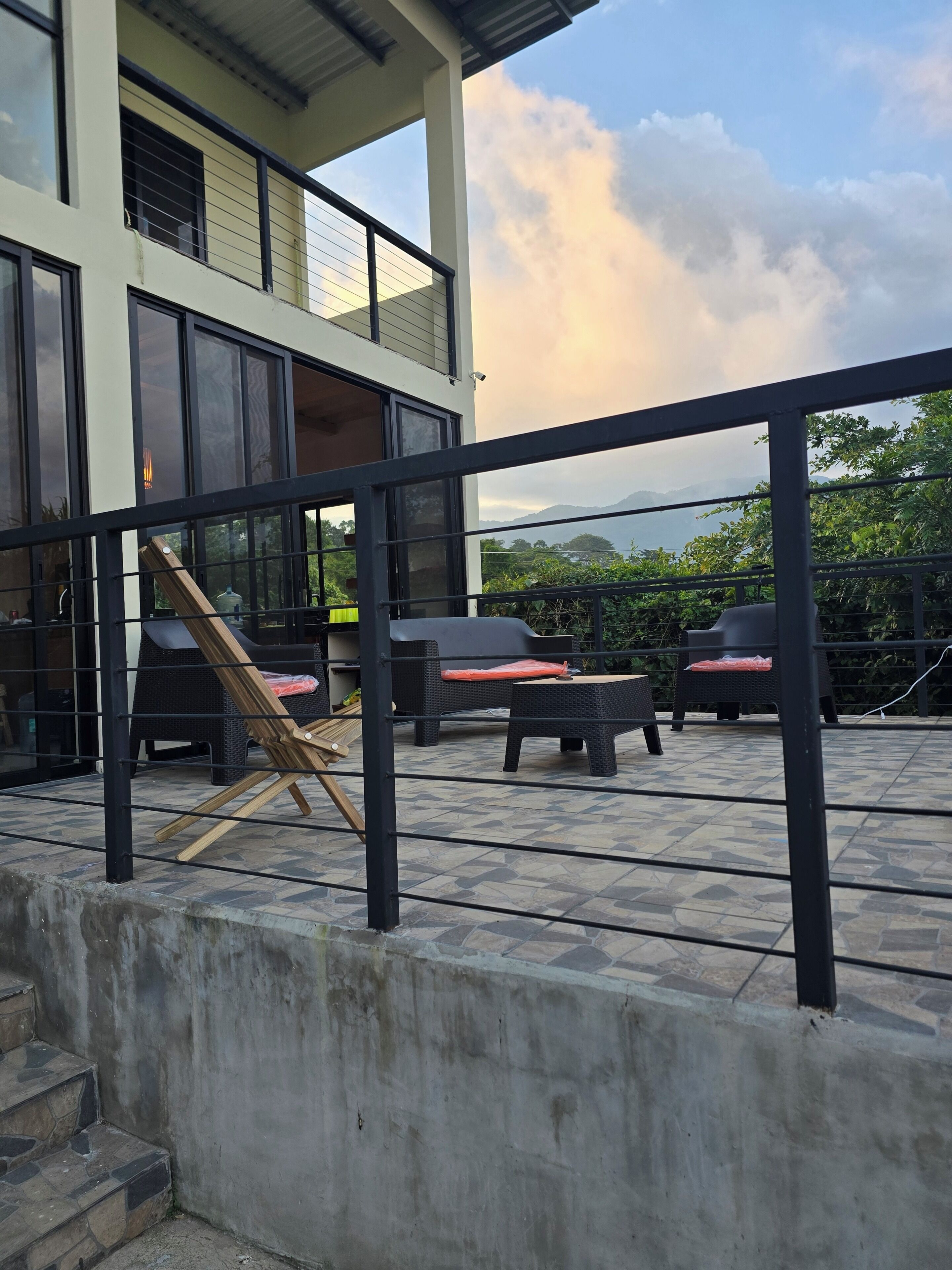 A modern outdoor seating area with wicker furniture and a view of mountains.