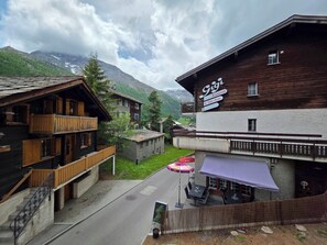 A mountain village with traditional wooden buildings, a restaurant named 'Gigi,' and a view of snow-capped mountains. - Am Biel 3 by Interhome (Saas-Fee)