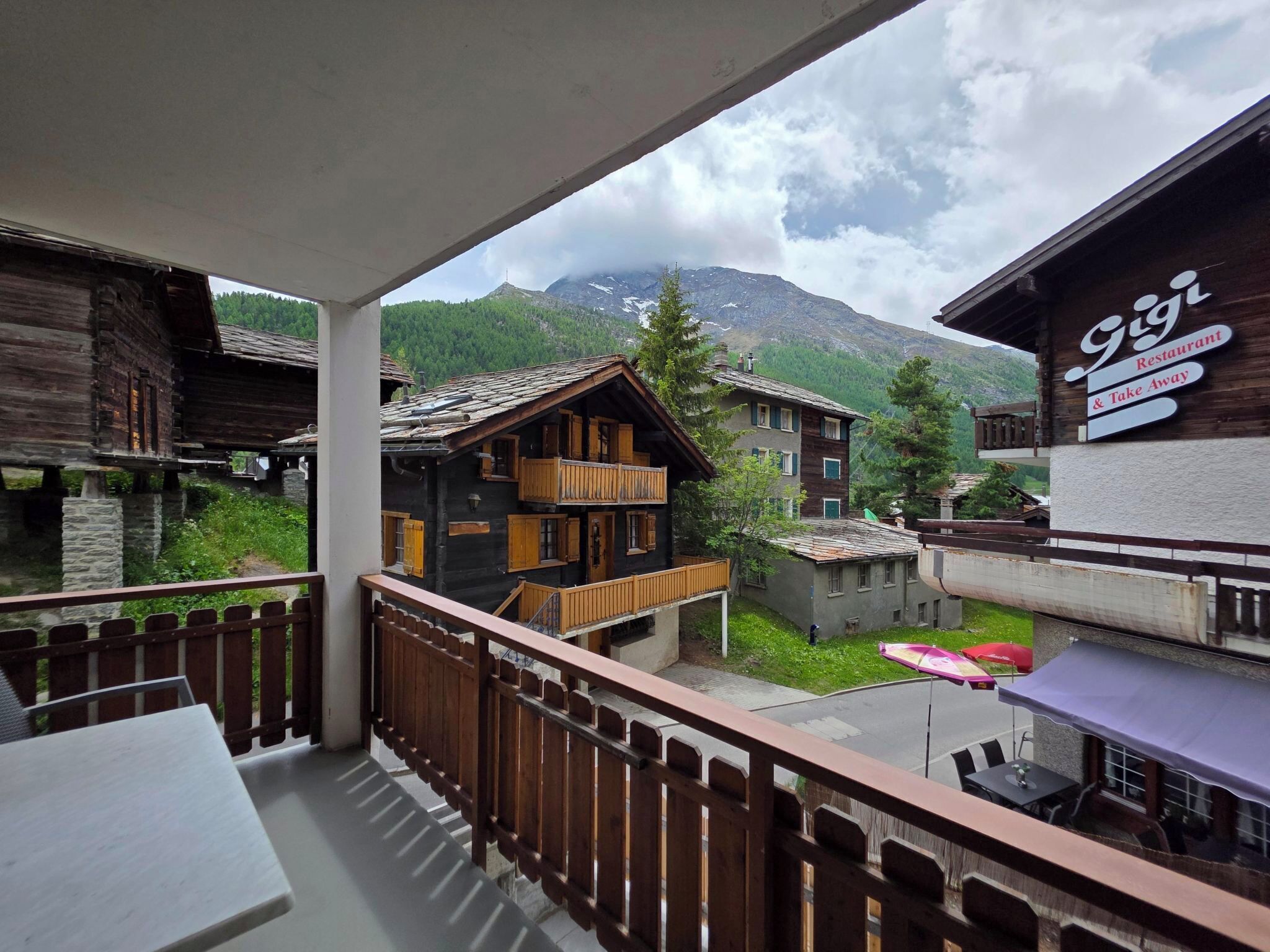 Ein Balkon mit Blick auf traditionelle Holzhäuser und einen Berg im Hintergrund.
