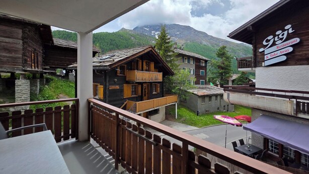 Ein Balkon mit Blick auf traditionelle Holzhäuser und einen Berg im Hintergrund.