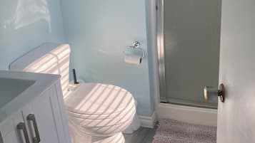 A bathroom with a toilet, a shower enclosure, and a sink.
