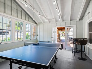 A ping pong table in a room with large windows and a door leading outside. - Welcome to the Boat House (Kelseyville)