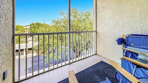 Un balcon donnant sur des arbres et un immeuble.