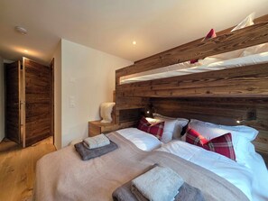 A room with a bunk bed, a bedside table, a chair, and a wardrobe. - Alphubel Unlimited 23 by Interhome (Saas-Fee)