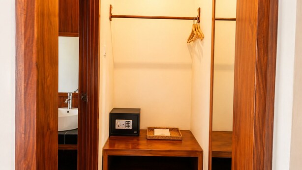 Ein kleines Badezimmer mit einem hölzernen Waschtisch, einem schwarzen Safe und einer Kleiderstange.