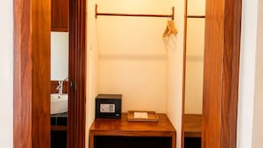 A small bathroom with a wooden vanity, a black safe, and a hanging clothes rack.