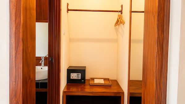 A small bathroom with a wooden vanity, a black safe, and a hanging clothes rack. - Delux Room resort in fabulous Kedewatan Ubud (Kedewatan ubud)