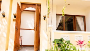 A hotel entrance with a wooden door, a number sign, and a window with curtains.