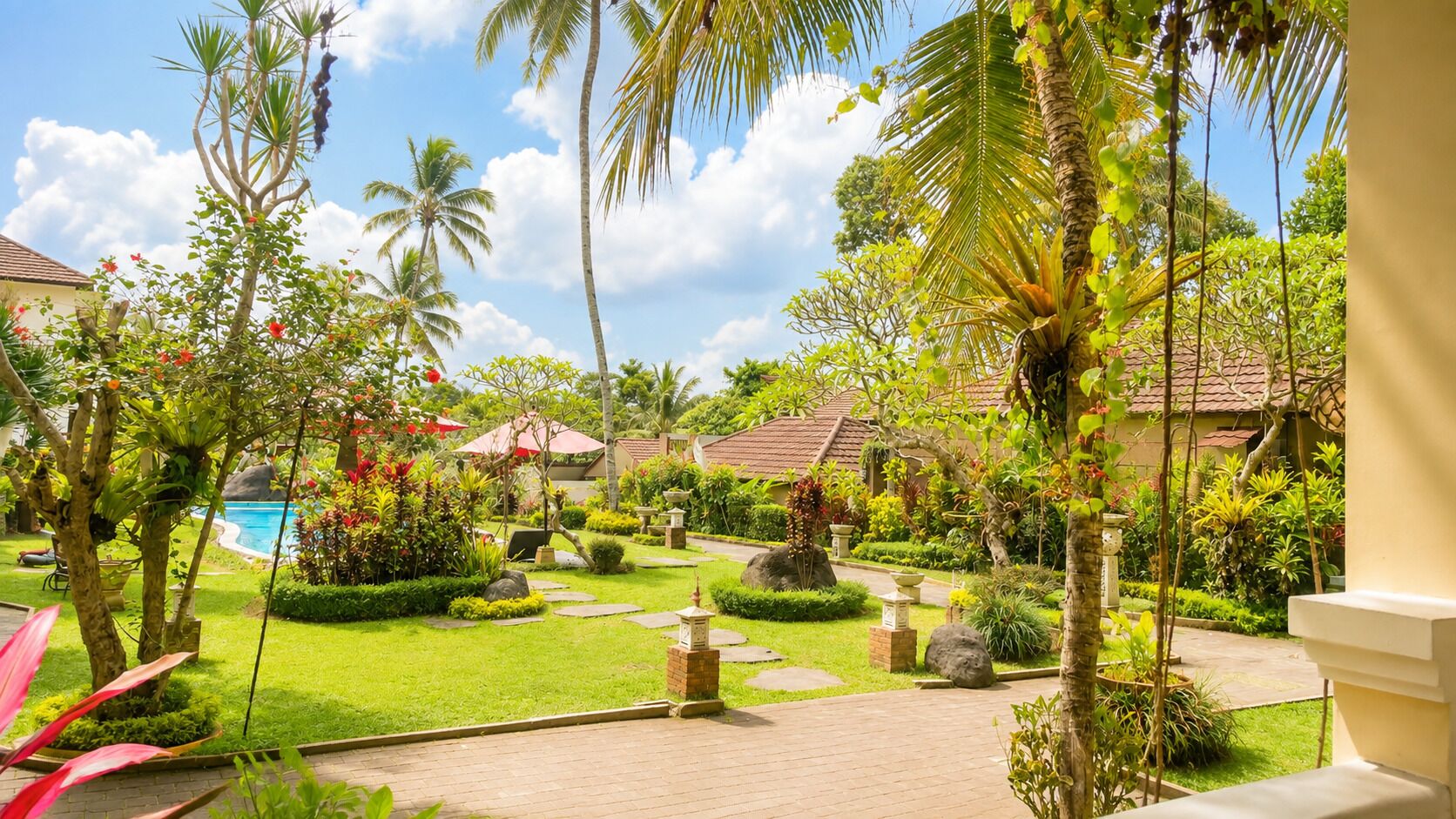 Um jardim tropical com piscina, palmeiras e gramado bem cuidado.