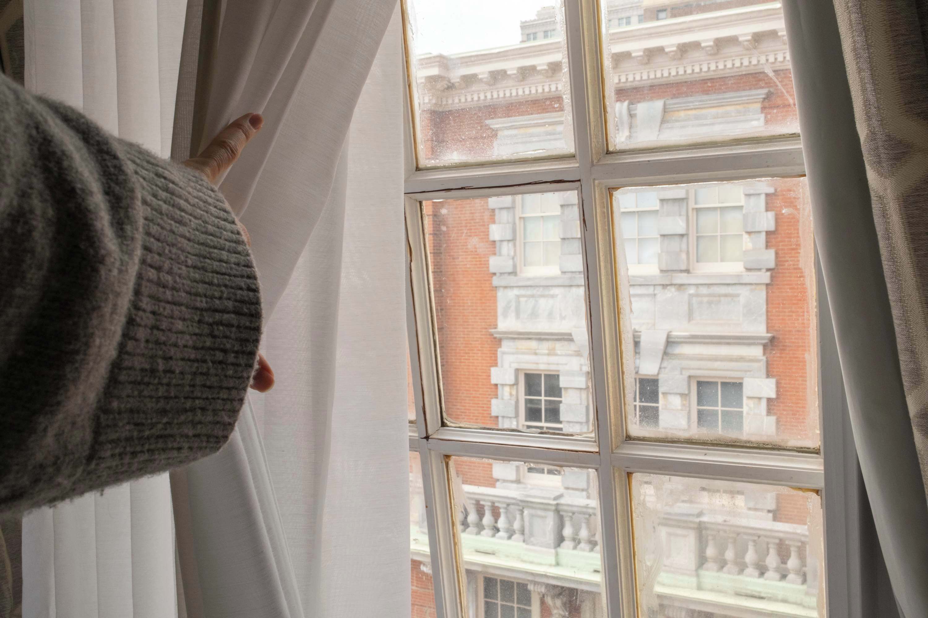 A window with a view of a building with multiple windows and a balcony.