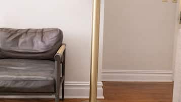 A room with a leather sofa, a tall floor lamp, wooden flooring, and white walls.