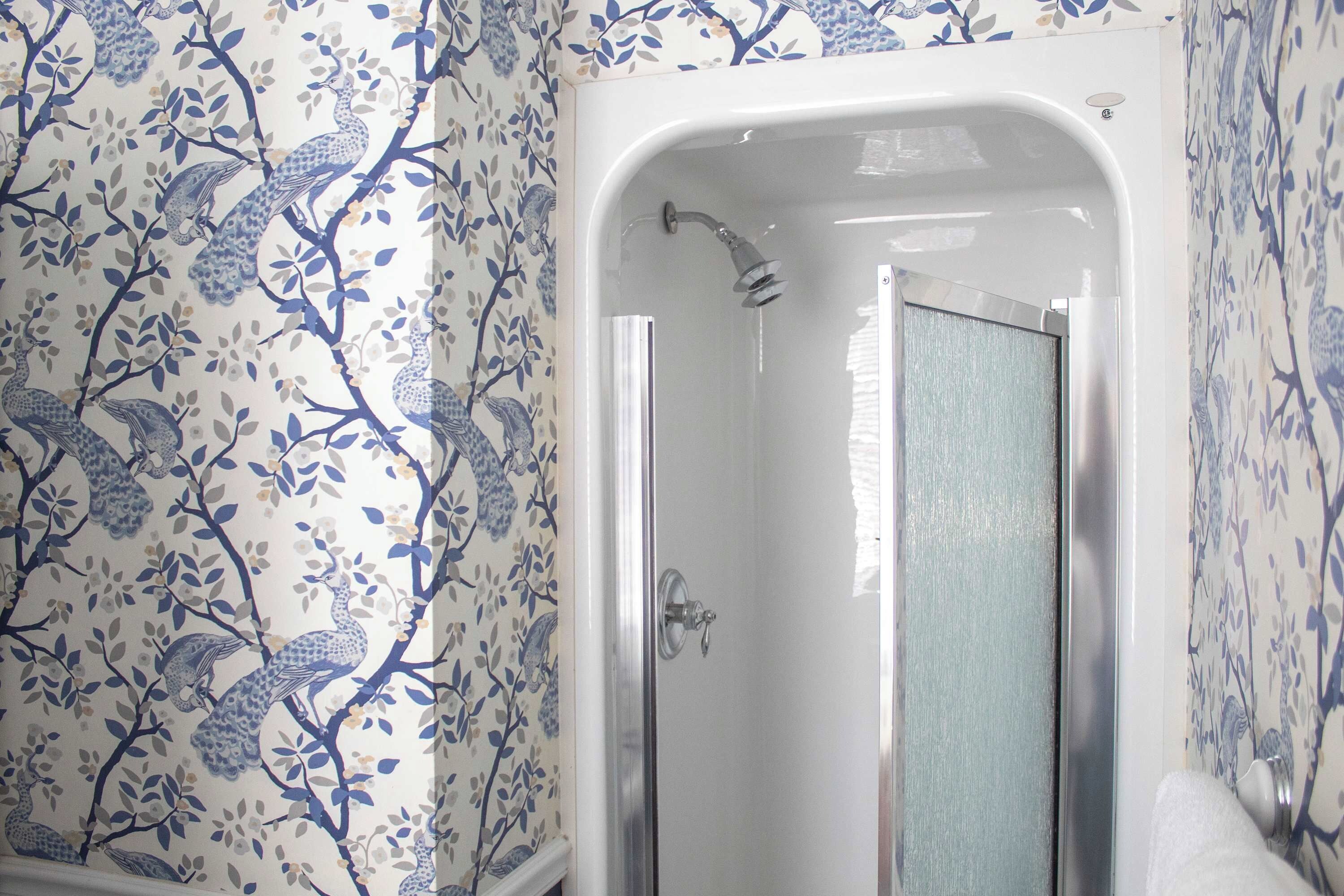 A bathroom with a shower enclosure and floral wallpaper.