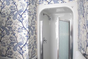 A bathroom with a shower enclosure and floral wallpaper. - Queen Double Room | StayCozy at The Arco (Philadelphia)