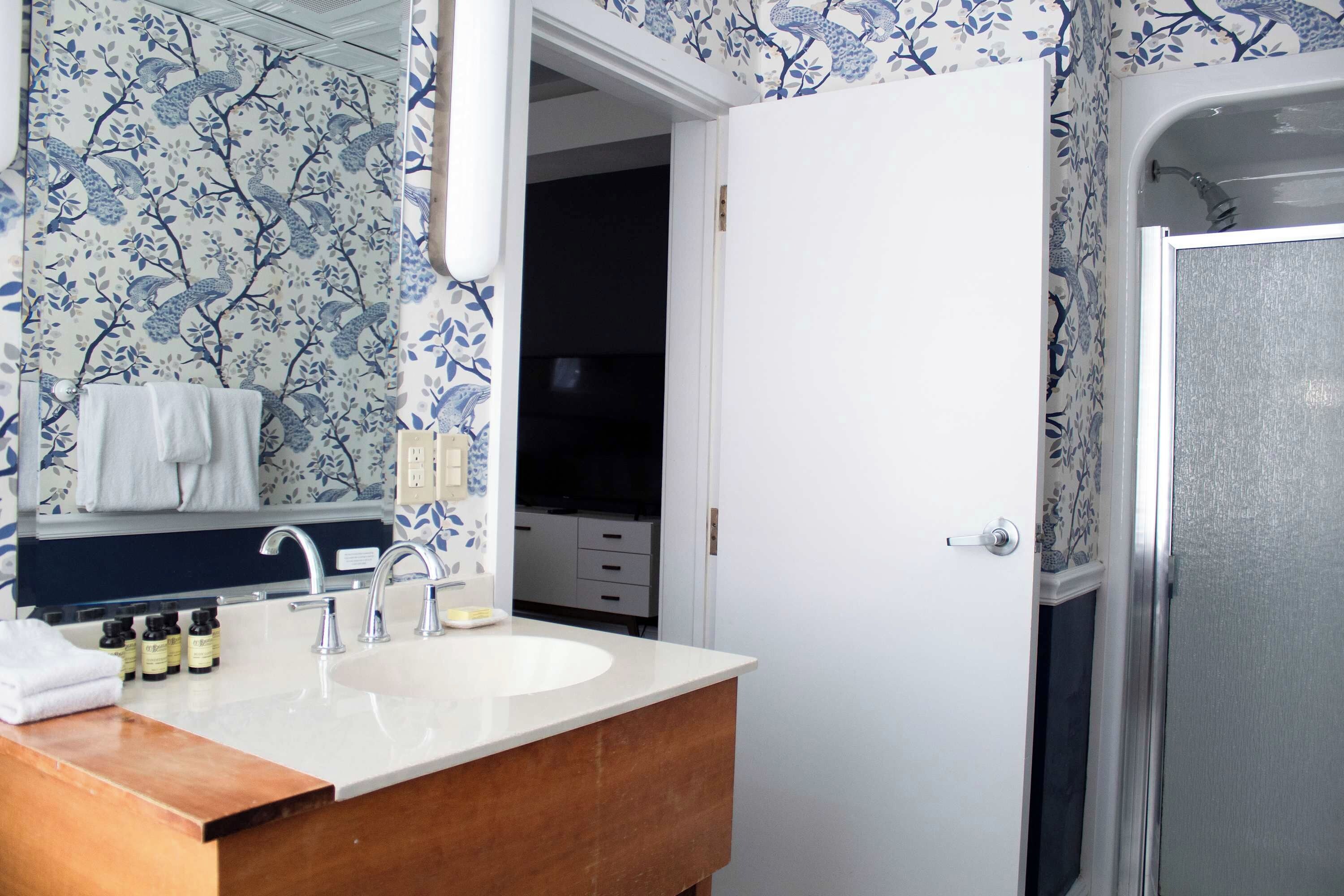A bathroom with a white sink, a mirror, and a shower area.