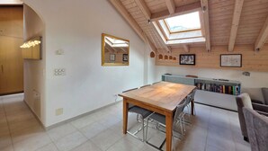 Ein Essbereich mit Holztisch und -stühlen, einem Oberlicht und einem Bücherregal mit Büchern.