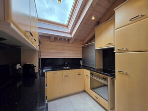 Eine moderne Küche mit Oberlichter, Holzschränken und einer schwarzen Arbeitsplatte.