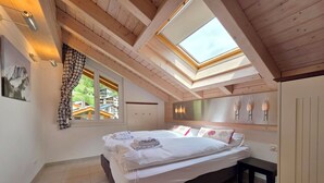 Ein Schlafzimmer mit Oberlicht, einem Bett mit ordentlich gefalteten Handtüchern und Blick auf die Stadt.