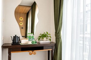 A hotel room with a wooden console table, a kettle, green bottles, a book, and a potted plant. - LUMA Phrom Phong (Bangkok)