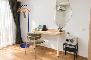 A room with a wooden desk, a chair, a mirror, an air conditioner, a radio, and a floor lamp. - LUMA Phrom Phong (Bangkok)