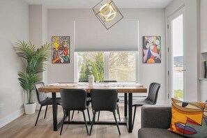 A dining area with a wooden table, black chairs, a potted plant, and abstract art on the walls. - Luxe Warrenville 4BR | Patio + Pickleball Court (Warrenville)