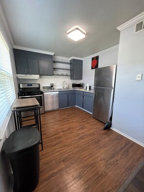 A modern kitchen with grey cabinets, stainless steel appliances, and a wooden floor. - Renovated Condo: Your home away from home (Decatur)