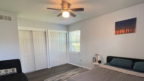 Ein Schlafzimmer mit Bett, Deckenventilator, Fenster und Tür.