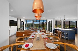 A modern dining area with a wooden table set for four, a large pendant light, and a view of the outdoors. - 10 The Terrace | Lake View | Hot Tub (Queenstown)