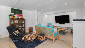 A living room with a sofa, a television, a bookshelf, and a coffee table. - 10 The Terrace | Lake View | Hot Tub (Queenstown)