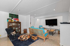 A living room with a sofa, a television, a bookshelf, and a coffee table. - 10 The Terrace | Lake View | Hot Tub (Queenstown)