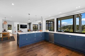 A modern kitchen with blue cabinets, a large island, and a view of the outdoors. - 10 The Terrace (Queenstown)