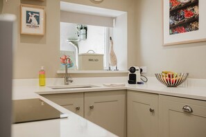 A modern kitchen with a sink, a bread box, and a fruit bowl on the counter. - Stunning Flat in Heart of Cheltenham (Cheltenham)