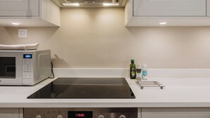 A kitchen with a microwave, a stove, and a sink. - Stunning Flat in Heart of Cheltenham (Cheltenham)