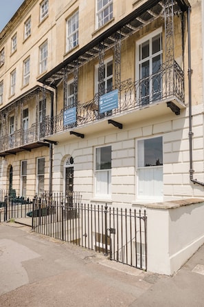A multi-story building with balconies, a white facade, and a black metal fence. - Stunning Flat in Heart of Cheltenham (Cheltenham)