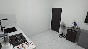 A compact kitchen with a gas stove, sink, and a small refrigerator.