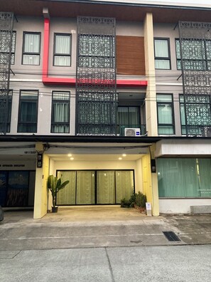 A multi-story building with a ground-level entrance, large windows, and a red accent on the facade. - 4BR Townhome  Sleeps 10  Near Nimman & MAYA mall (Chang Wat Chiang Mai)