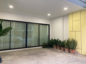A room with a large sliding glass door, potted plants, and a yellow wall. - 4BR Townhome  Sleeps 10  Near Nimman & MAYA mall (Chang Wat Chiang Mai)