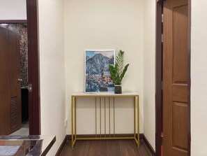 Un corridoio con un tavolo consolle che espone una cornice con un'immagine e una pianta in vaso.