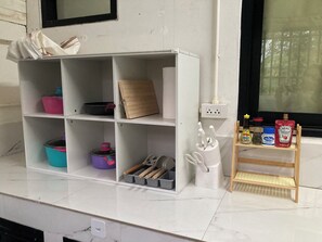 A kitchen counter with a white storage unit containing kitchen utensils, pots, and a cutting board. - 4BR Townhome  Sleeps 10  Near Nimman & MAYA mall (Chang Wat Chiang Mai)