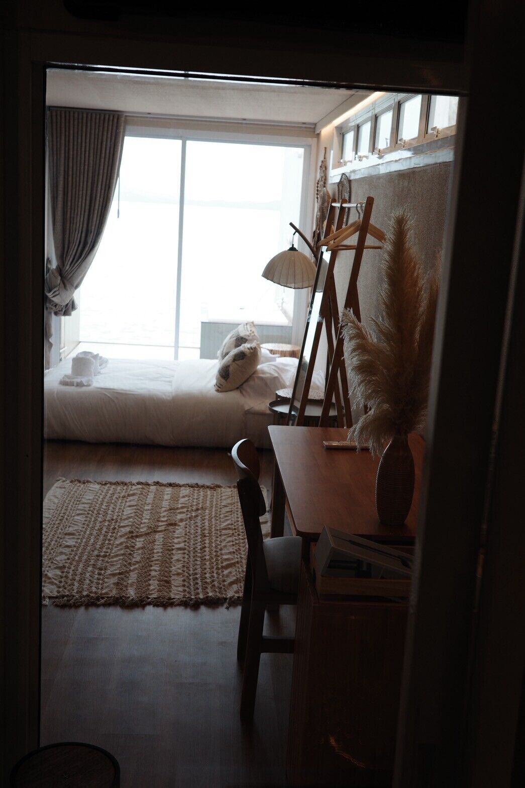 Una habitación con una cama, un escritorio con lámpara y una ventana con cortinas.