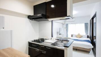 A compact kitchen with a stove, sink, and dark cabinets.