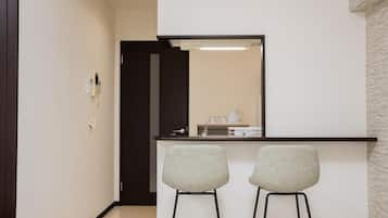 A hallway leading to a kitchenette with two bar stools and a mirror above the counter.