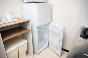Eine kleine Küche mit einem weißen Kühlschrank, einer Holzablage und einem Edelstahl-Spülbecken.