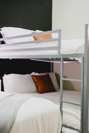 A bunk bed with a ladder, white bedding, and a brown pillow. - Modern City Stay | Pool, Gym & Valet Parking (Dallas)