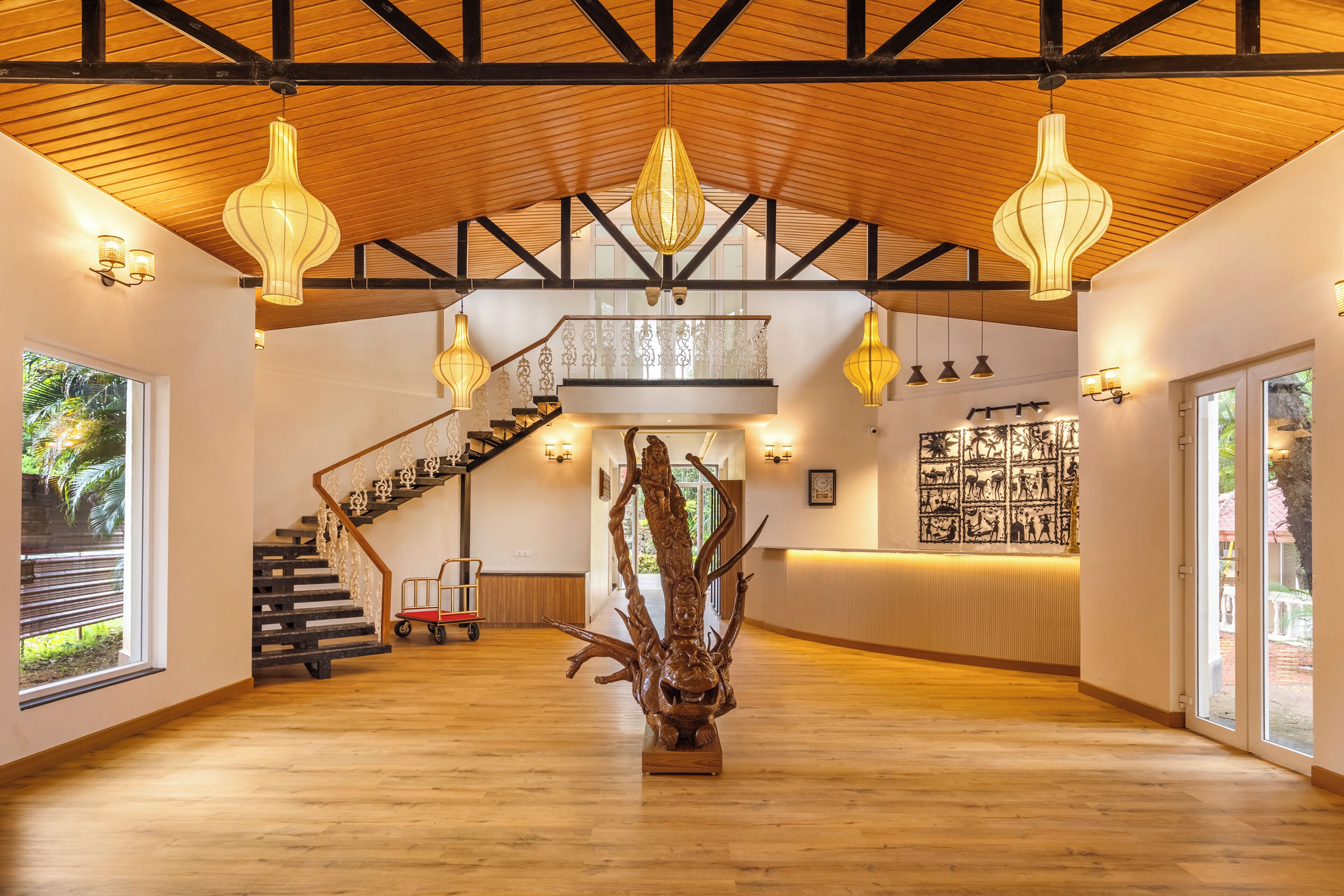 A spacious lobby with a wooden floor, a staircase, and a reception desk.